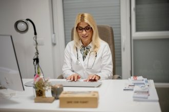 Лікарка оформлює документи за комп'ютером під час консультації пацієнта