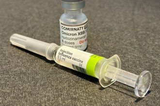 Шприц із вакциною від грипу і флакон вакцини від COVID-19